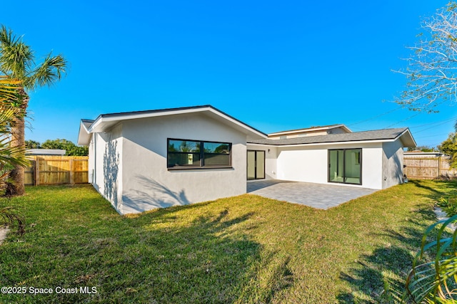 back of house featuring stucco siding, a lawn, a patio, and fence