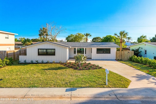 view of front of home featuring board and batten siding, concrete driveway, fence, and a front lawn