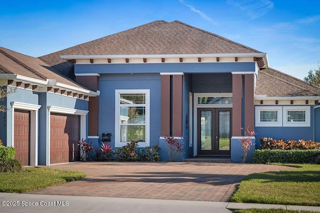 view of front of property featuring french doors, an attached garage, and stucco siding