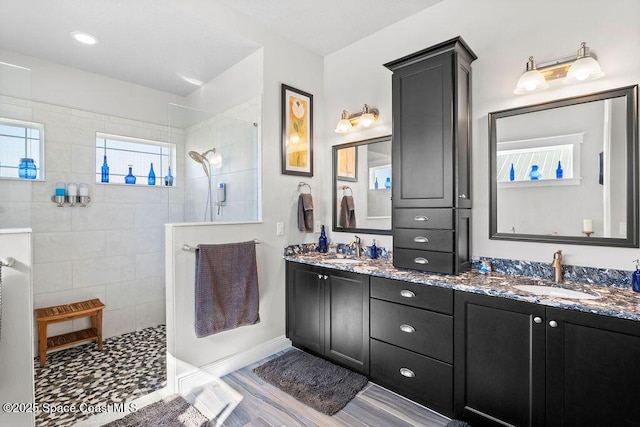 full bathroom with double vanity, a walk in shower, and a sink