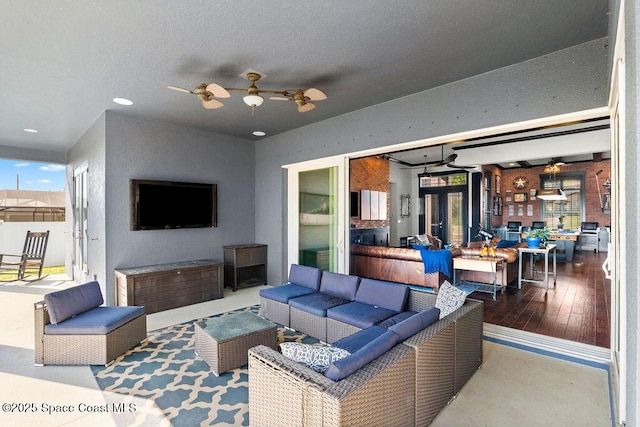 living area featuring plenty of natural light, a textured ceiling, ceiling fan, and wood finished floors