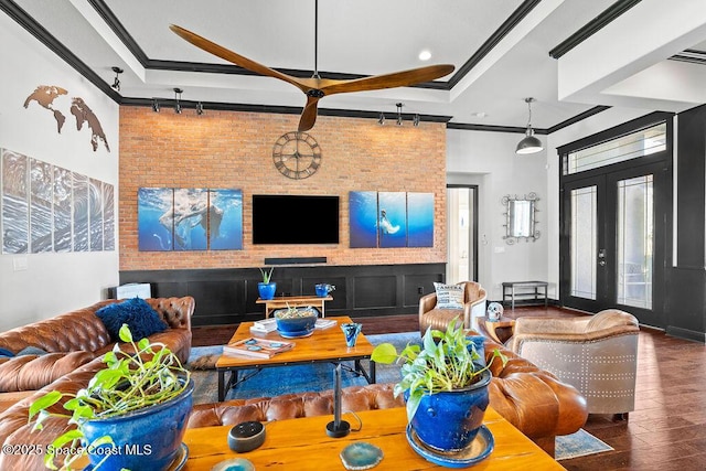 living room featuring french doors, brick wall, wood finished floors, and crown molding