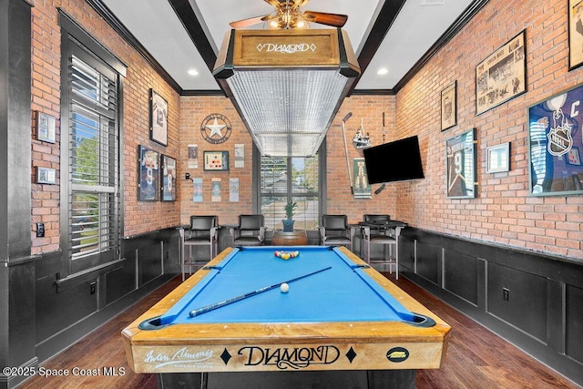 playroom featuring brick wall, crown molding, beam ceiling, wainscoting, and wood finished floors