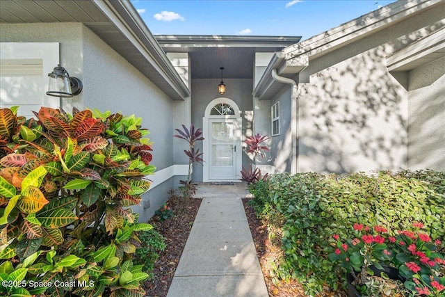 doorway to property with a garage and stucco siding