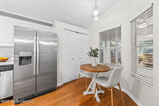 dining area with baseboards, light wood-style floors, and a textured ceiling