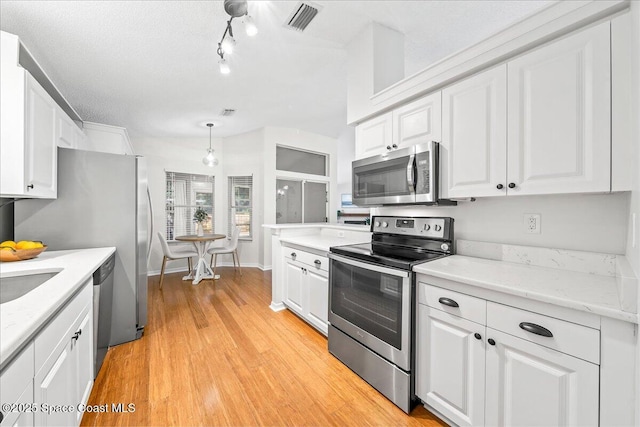 kitchen with white cabinetry, light countertops, light wood-style flooring, and stainless steel appliances