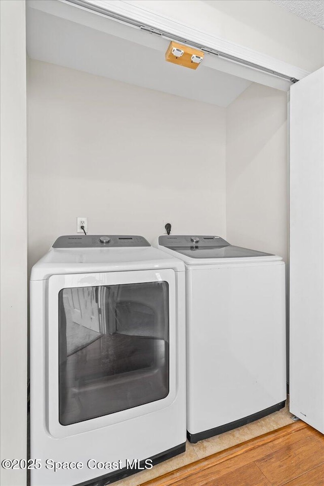 clothes washing area featuring laundry area, independent washer and dryer, and light wood-style floors