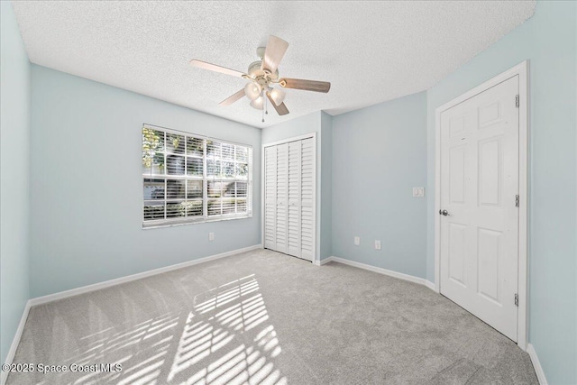 unfurnished room with a textured ceiling, a ceiling fan, baseboards, and carpet floors