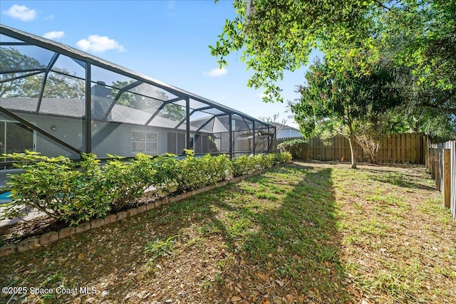 view of yard with glass enclosure and a fenced backyard