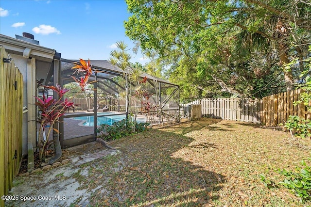 view of yard with a lanai, fence, a fenced in pool, and a patio