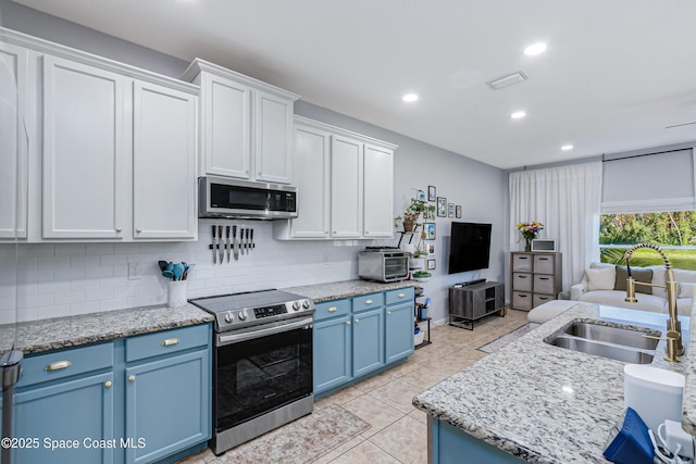 2705 Revolution St Unit 106, Melbourne, FL 32935 - kitchen with blue cabinetry, a sink, stainless steel appliances, open floor plan, and tasteful backsplash
