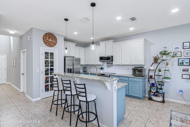 2705 Revolution St Unit 106, Melbourne, FL 32935 - kitchen featuring visible vents, light stone counters, a kitchen breakfast bar, stainless steel appliances, and light tile patterned floors