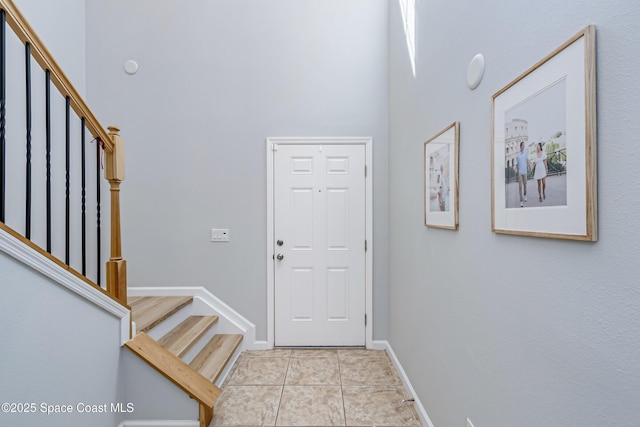 2705 Revolution St Unit 106, Melbourne, FL 32935 - entryway featuring baseboards, a high ceiling, light tile patterned flooring, and stairs