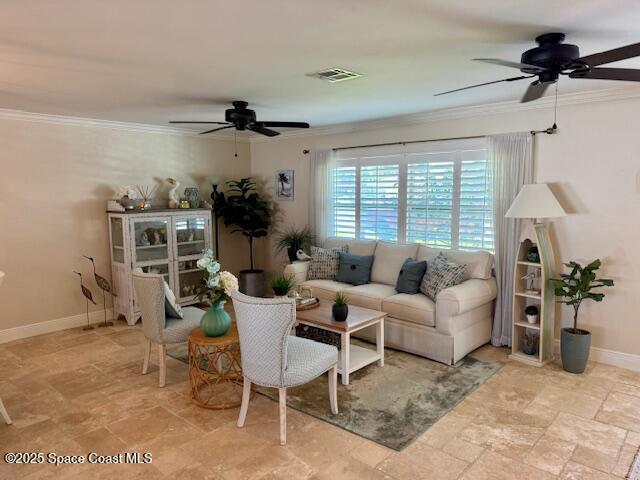 living room featuring a ceiling fan, baseboards, visible vents, ornamental molding, and stone finish floor