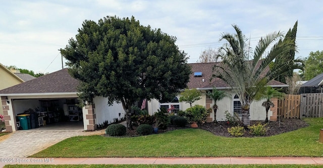 view of front of house featuring a shingled roof, stucco siding, a front lawn, a garage, and decorative driveway