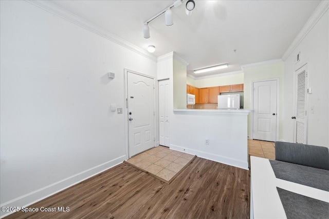 entrance foyer featuring light wood-style flooring, baseboards, ornamental molding, and rail lighting