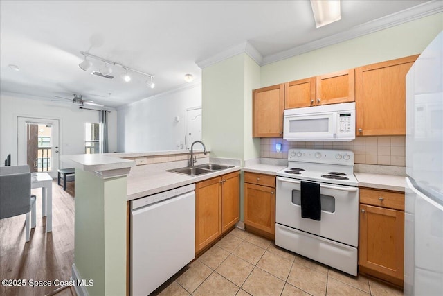 kitchen with white appliances, a peninsula, ornamental molding, a sink, and backsplash