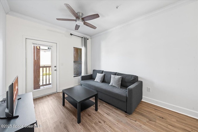 living room featuring ceiling fan, baseboards, light wood-type flooring, and ornamental molding