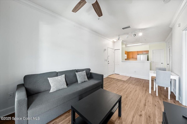 living area featuring a ceiling fan, baseboards, visible vents, light wood finished floors, and ornamental molding