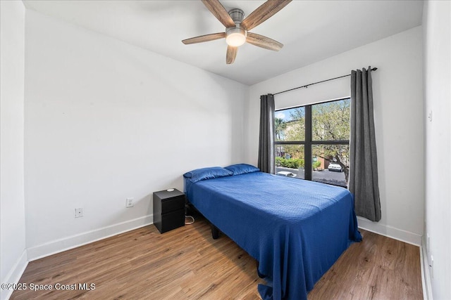 bedroom with a ceiling fan, baseboards, and wood finished floors