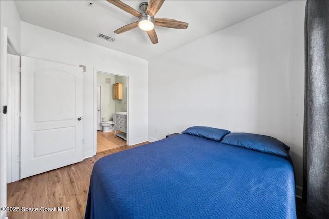 bedroom with visible vents, ensuite bath, wood finished floors, and a ceiling fan