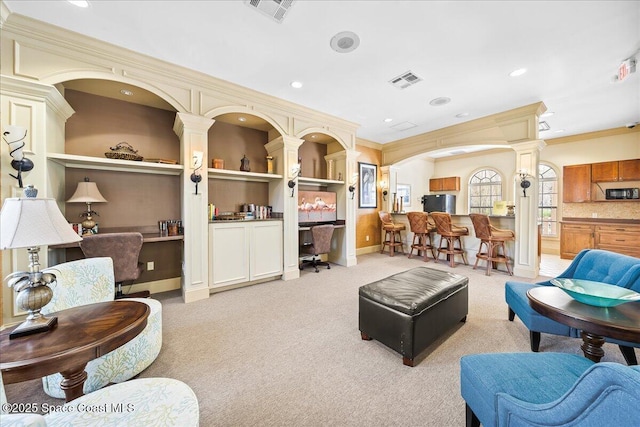 living room with visible vents, light colored carpet, crown molding, and decorative columns