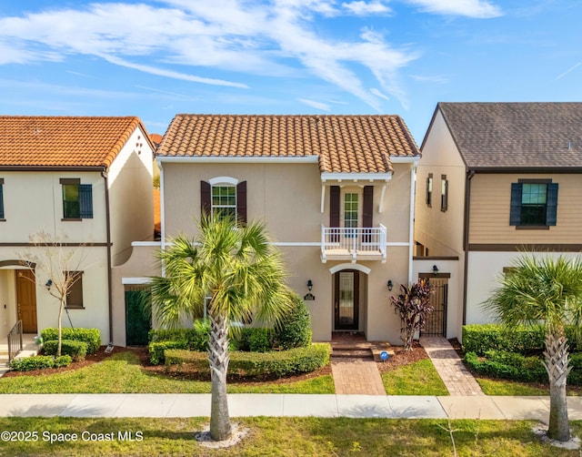 view of front of house featuring a gate, stucco siding, a balcony, and a tiled roof