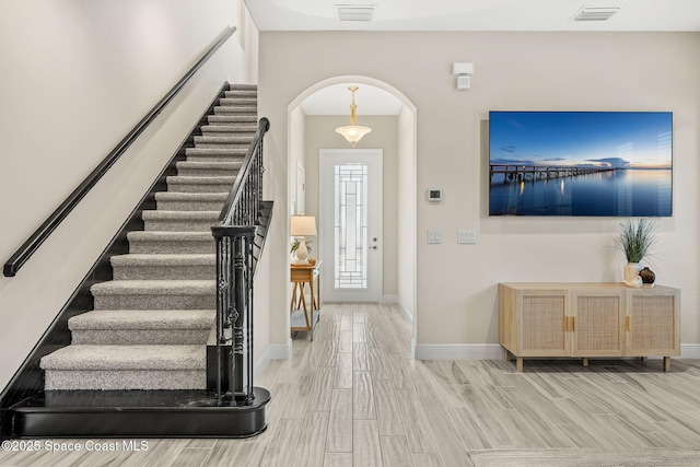 entryway featuring wood finished floors, arched walkways, visible vents, and baseboards