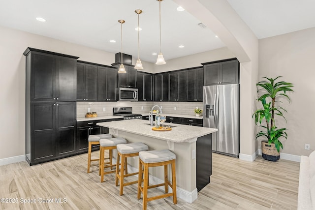 kitchen with a sink, tasteful backsplash, appliances with stainless steel finishes, and dark cabinets