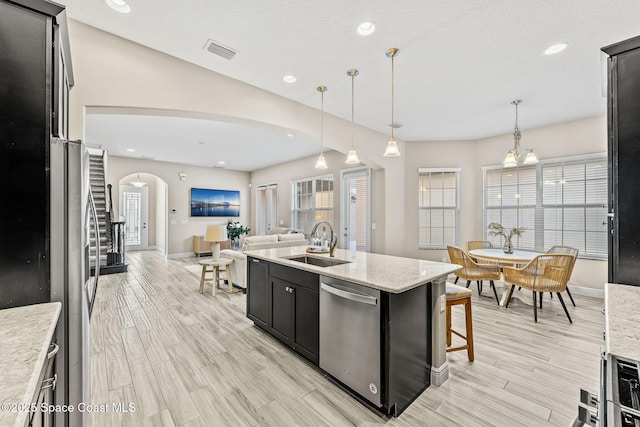 kitchen featuring visible vents, a sink, dark cabinetry, arched walkways, and appliances with stainless steel finishes