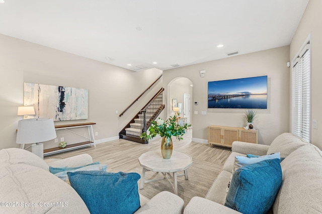 living room featuring visible vents, baseboards, stairs, wood finished floors, and arched walkways