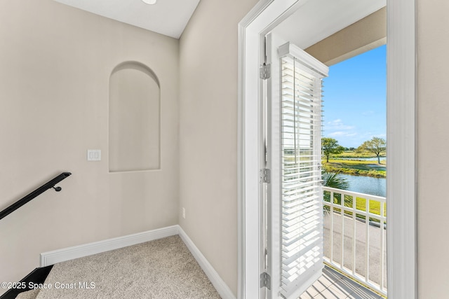 doorway to outside with carpet flooring, baseboards, and a water view