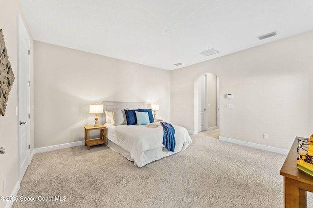 bedroom with arched walkways, visible vents, baseboards, and carpet floors