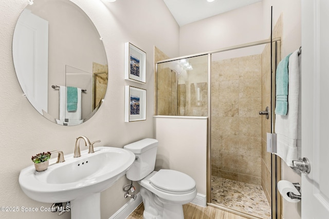 full bathroom featuring a sink, wood finished floors, toilet, and a stall shower