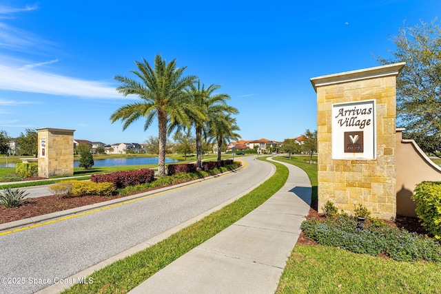 view of street with sidewalks, curbs, and a water view