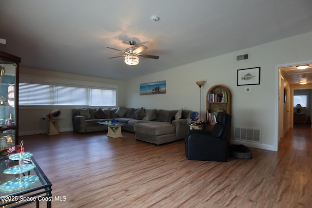 living area with visible vents, baseboards, ceiling fan, and wood finished floors