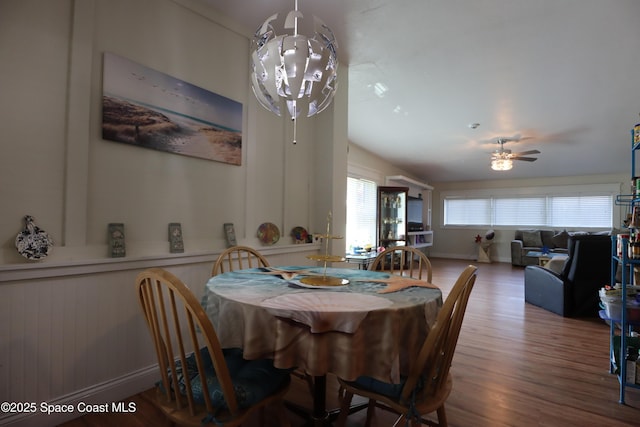 dining room featuring ceiling fan with notable chandelier, vaulted ceiling, and wood finished floors