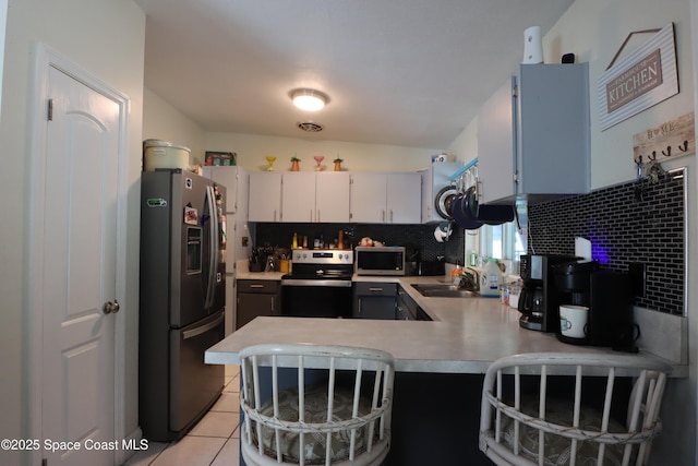 kitchen with tasteful backsplash, appliances with stainless steel finishes, light countertops, and a sink