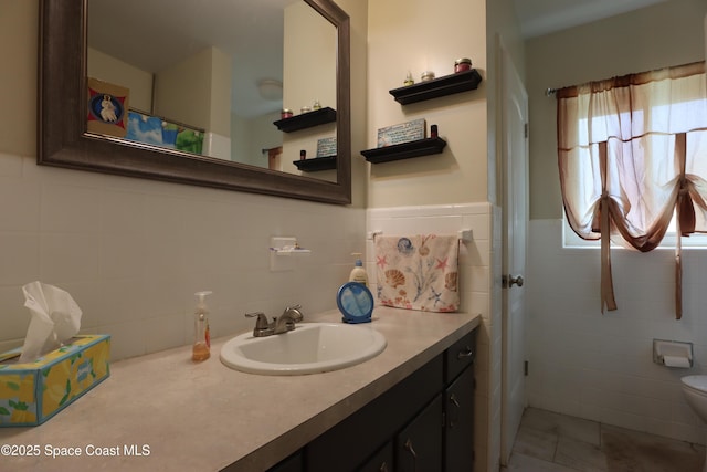 bathroom with wainscoting, toilet, vanity, and tile walls