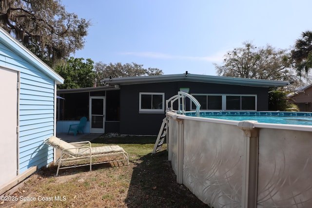 rear view of property featuring an outdoor pool and a sunroom