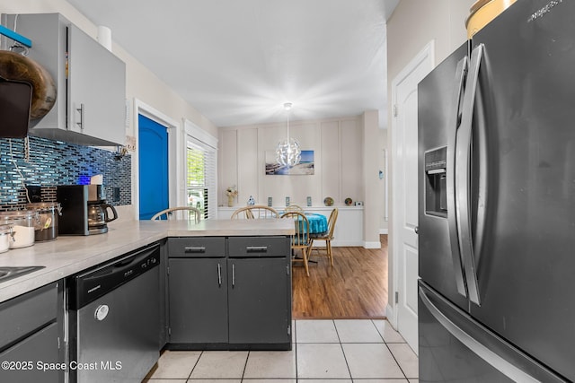 kitchen featuring decorative backsplash, dishwasher, light countertops, a peninsula, and refrigerator with ice dispenser
