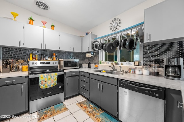 kitchen with stainless steel appliances, backsplash, vaulted ceiling, visible vents, and a sink