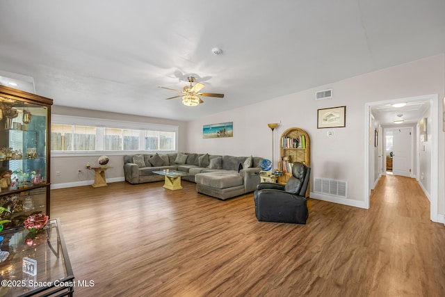 living area featuring wood finished floors, visible vents, baseboards, and ceiling fan