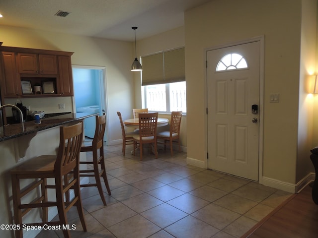 interior space featuring light tile patterned floors, baseboards, and visible vents