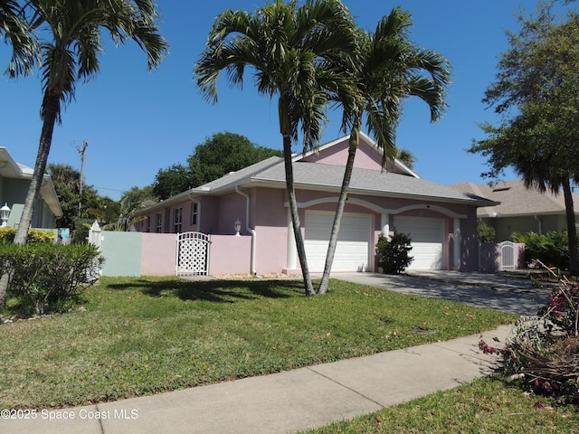 view of property exterior with fence, stucco siding, a yard, an attached garage, and a gate