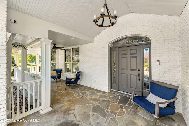 property entrance with covered porch, brick siding, and ceiling fan