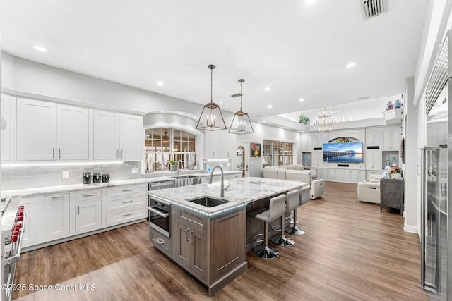 kitchen featuring visible vents, open floor plan, stainless steel oven, an inviting chandelier, and a sink