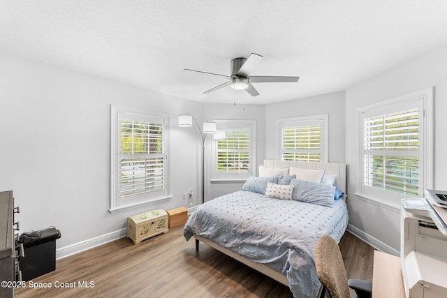 bedroom featuring baseboards, wood finished floors, and a ceiling fan