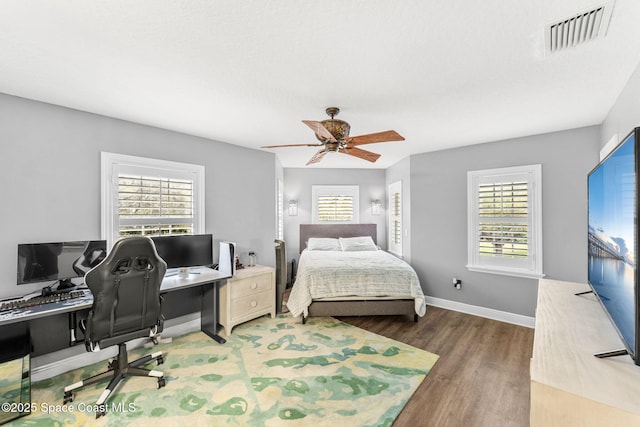 bedroom with multiple windows, wood finished floors, visible vents, and baseboards