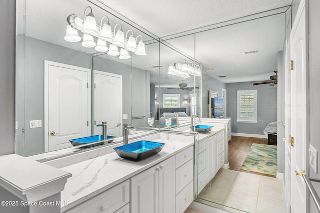 full bath with a textured ceiling, ensuite bath, tile patterned flooring, ceiling fan, and vanity